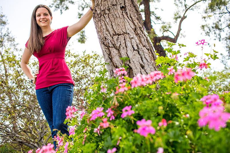 Deusch standing next to flowers and tree